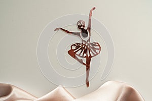 Paper pink ballerina performing a pirouette on a background of pink draped fabric