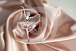 Paper pink ballerina performing a pirouette on a background of pink draped fabric