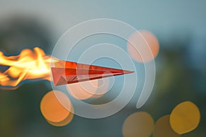 paper plane on fire midflight with blurred background photo