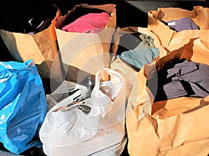 Paper and plastic bags containing clothing and shoes stacked together photo