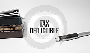 Paper plate, glasses, notepad in stack,pen and text TAX DEDUCTIBLE on business card