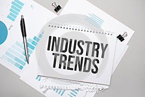 Paper plate with text INDUSTRY TRENDS. Diagram, notepad and blue background