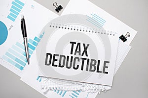 Paper plate with text TAX DEDUCTIBLE. Diagram, notepad and blue background