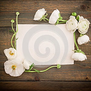 Paper post card and white flowers on wooded background. Flat lay, top view. Vintage background.