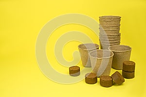 Paper pots for seedlings, and coconut tablets, on a yellow background. photo