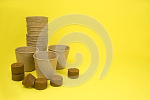 Paper pots for seedlings, and coconut tablets, on a yellow background. photo