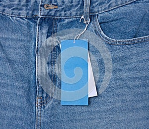 Paper price tag on a rope tied to the waistband of blue jeans