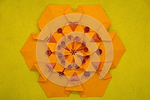 Paper quilling and origami composition. Creative orange hexagon isolated on yellow background.