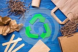 Paper recycle sign with paper and carton garbage on blue wooden background top view