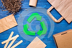 Paper recycle sign with paper and carton garbage on blue wooden background top view