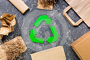 Paper recycle sign with paper and carton garbage on grey table background top view