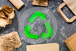 Paper recycle sign with paper and carton garbage on grey table background top view