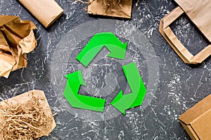 Paper recycle sign with paper and carton garbage on grey table background top view