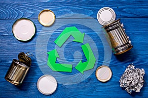 Paper recycle sign with steel garbage on blue table background top view