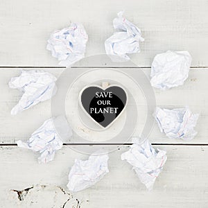 Paper recycling concept - crumpled paper around a blackboard in shape of heart and text Save our planet