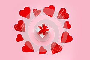 Paper red hearts around a gift box on a pink background. Happy Valentine\'s day concept. Valentine\'s day greeting card