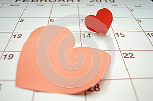 Paper red hearts marking 14 february Valentines day on white calendar