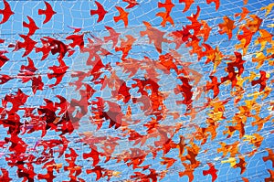 Paper red and orange birds on a rope mesh against a blue sky. A symbol of hope and healing in difficult times.