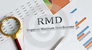 Paper with Required Minimum Distributions RMD on a table with pen ,chart , magnifier