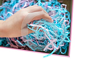 Paper shavings. Colored cut paper for packaging. Child`s hand examines