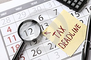 Paper sheet with text TAX DEADLINE and magnifying glass on calendar