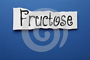 Paper sheet with word Fructose on blue background, top view. Space for text