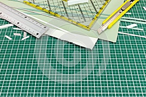 Paper sheets with metal ruler and utility knife on green cutting