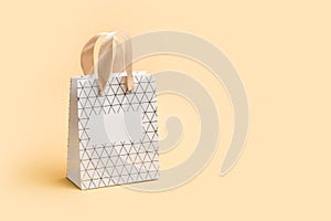 Paper shopping bag on beige background. Holiday sale concept in monochrome tones