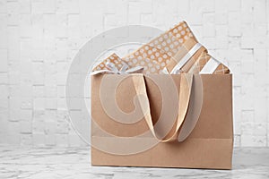 Paper shopping bag with handles full of gift boxes on table