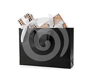 Paper shopping bag with handles full of gift boxes on white background.