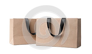 Paper shopping bags with ribbon handles on white background.