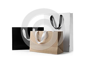 Paper shopping bags with ribbon handles on white background.