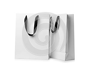 Paper shopping bags with ribbon handles on white background.