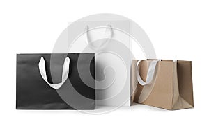 Paper shopping bags with ribbon handles on white background.