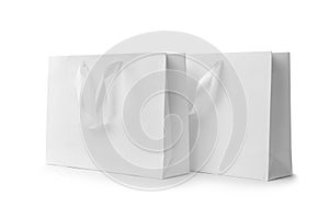 Paper shopping bags with ribbon handles on white background.