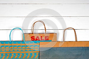Paper shopping bags on a white wooden background.