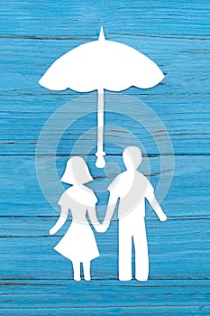 Paper silhouette of man and woman holding hands under umbrella