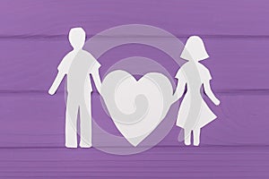 Paper silhouette of man and woman holds big heart