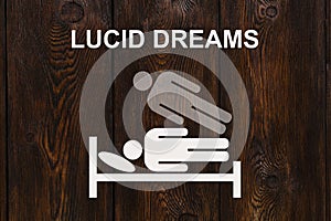 Paper sleeping man on bed with text LUCID DREAMS photo