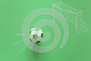 Paper soccer ball flying into goal painted by chalk on green background. Origami. Paper craft. Soccer game concept