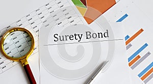 Paper with Surety Bond on a table with pen, chart and magnifier