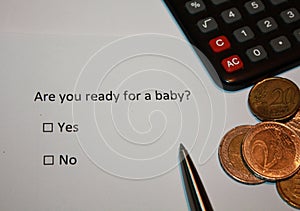 Paper with survey question: Are you ready for a baby? Yes or No box and euro coins and calculator. Responsible parenthood planning