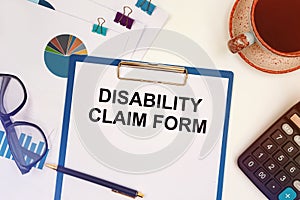 Paper with text - DISABILITY CLAIM FORM on the table, calculator and cup of coffee