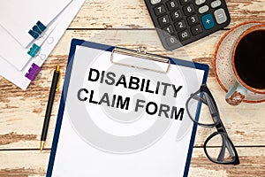 Paper with text - DISABILITY CLAIM FORM on the table, calculator and cup of coffee