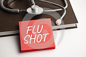 Paper with text FLU SHOT on blue background with stethoscope and pills