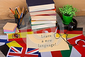 paper with text & x22;Learn a new language!& x22;, flags, books, headphones, pencils