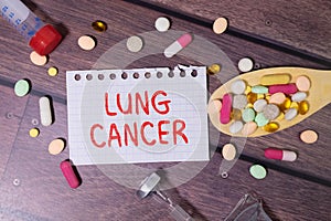 Paper with text LUNG CANCER on blue background with stethoscope and pills.