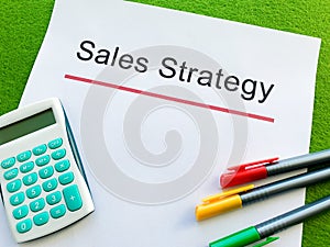 Paper with text sales strategy on green background