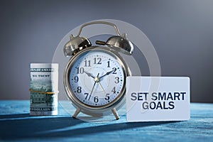 Paper with text Set Smart Goals and money, alarm clock