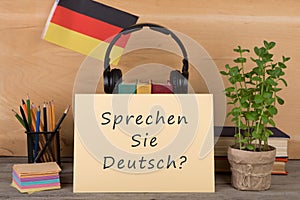 paper with text & x22;sprechen sie deutsch?& x22;, flag of the Germany, books, headphones, pencils